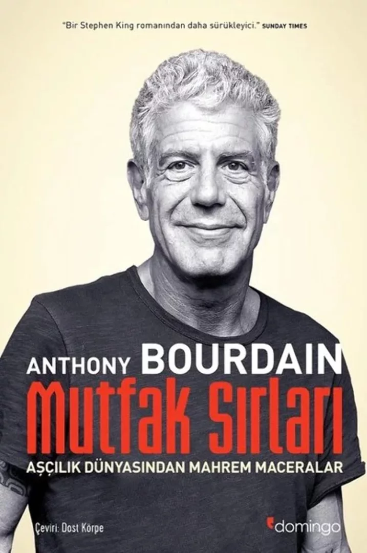 Anthony Bourdain'in Mutfak Sırları: Aşçılık Dünyasından Mahrem Maceralar adlı kitabının kapağında, gri saçlı, koyu renk tişörtlü, sağ kolunda dövmesi görünen ve tebessüm eden Bourdain okuyucuya bakarken; bu eser, onun mutfak ve seyahat dünyasına nasıl farklı bir bakış açısı getirdiğini anlamak için kilit nitelikte bir başlangıç noktası sunuyor.