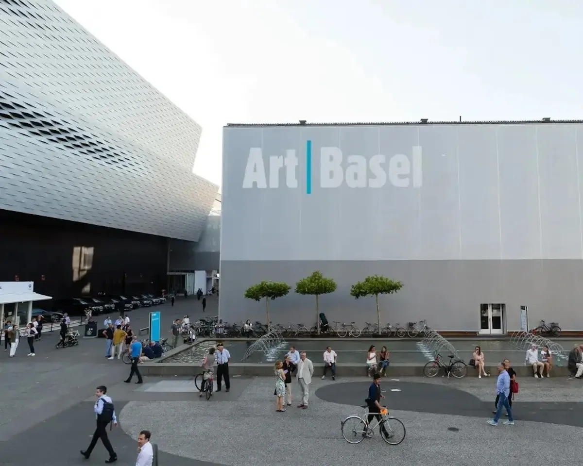 Basel gezilecek yerler arasında Art Basel fuar merkezi, modern cephesi, şehir meydanı ve canlı etkinlik atmosferiyle görülüyor.