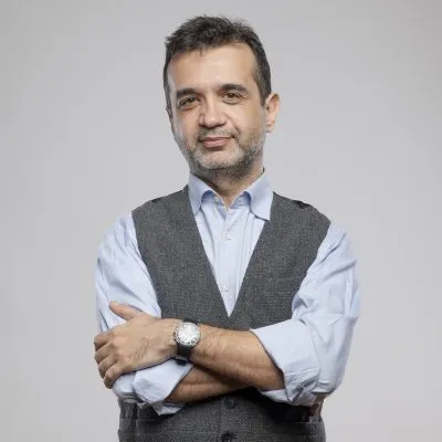 Kısa koyu saçları ve hafif sakalları olan Burak Goral, açık mavi gömleği ve gri yeleğiyle kollarını kavuşturmuş bir şekilde, dijital dönüşüm ve liderlik konularındaki uzmanlığını paylaşmaya hazır bir ifadeyle kameraya bakıyor.