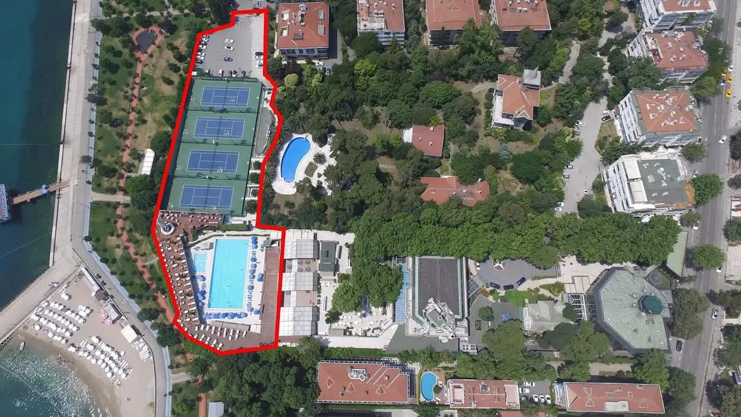 İstanbul Kadıköy'deki Büyük Kulüp'ün kuşbakışı görüntüsü, kırmızı bir hatla çevrelenmiş geniş kompleksini, dört adet mavi tenis kortunu, iki büyük yüzme havuzunu ve denize nazır yemyeşil bahçeleriyle birlikte detaylıca gösteriyor.
