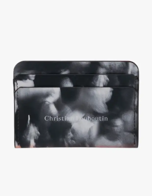 Christian Louboutin markalı, gri ve beyaz renklerdeki bulut veya duman gibi soyut desenlere sahip, ön yüzünde Christian Louboutin yazısı bulunan, birden fazla kart yuvası olan ve alt kenarından belirgin kırmızı astar detayının göründüğü modern bir kartlık.