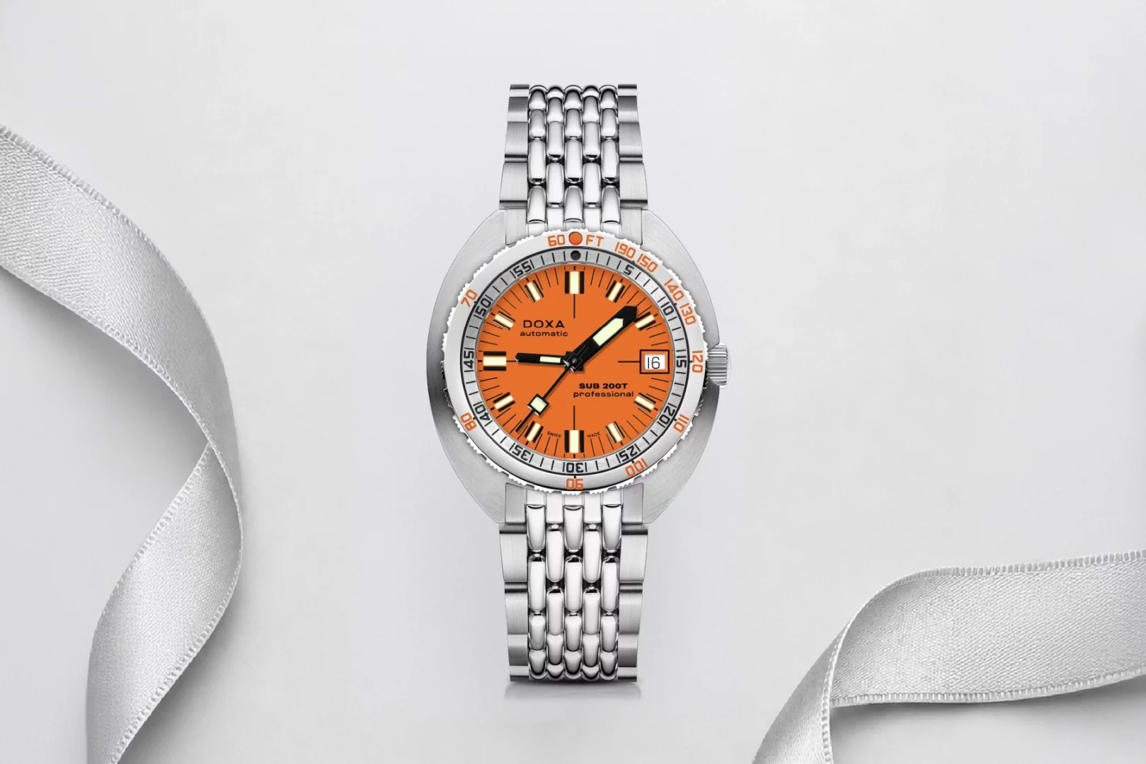 Doxa Automatic SUB 200T Professional dalış saati, parlak turuncu kadranı ve paslanmaz çelik bileziğiyle beyaz zeminde zarif bir gümüş kurdele üzerinde duruyor, Babalar Günü için özel bir saat hediyesi önerisini vurguluyor.