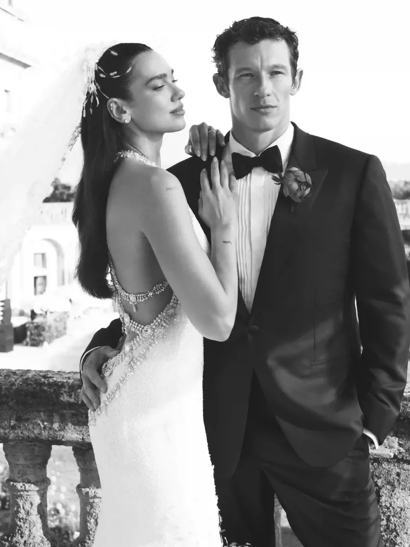 Sicilya'daki düğün kutlamalarından, Dua Lipa'nın sırt dekolteli ve işlemeli Chanel Haute Couture gelinliğiyle Callum Turner'ın smokinli olarak samimi poz verdiği, aşkın ve modanın zarafetini yansıtan siyah beyaz bir fotoğraf.
