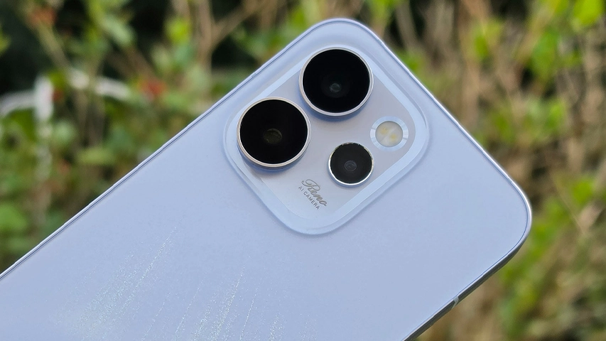 Açık mor renkteki bir akıllı telefonun arka yüzündeki büyük kamera modülü, biri üstte, biri solda ve biri altta olmak üzere üç lensi, bir flaşı ve Reno AI CAMERA yazısını net bir şekilde gösterirken, bulanık yeşil bir arka plan en iyi kameralı telefonlar için ideal bir dış çekim ortamı sunuyor.
