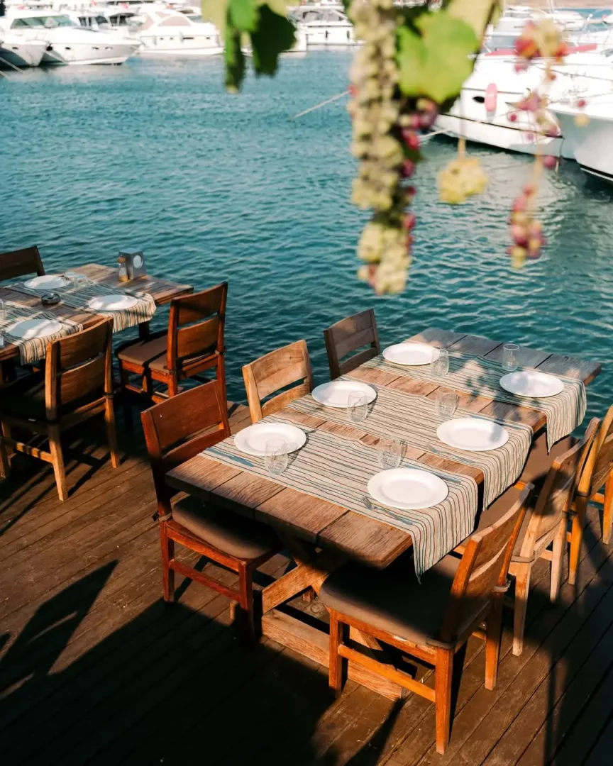 Alaçatı'nın en iyi mekanları arasında yer alan Ferdi Baba'nın Port Alaçatı Marina'daki şubesi, denize sıfır konumu, teknelerle çevrili manzarası ve uzun rakı-balık sofralarına eşlik eden eşsiz atmosferiyle öne çıkıyor.