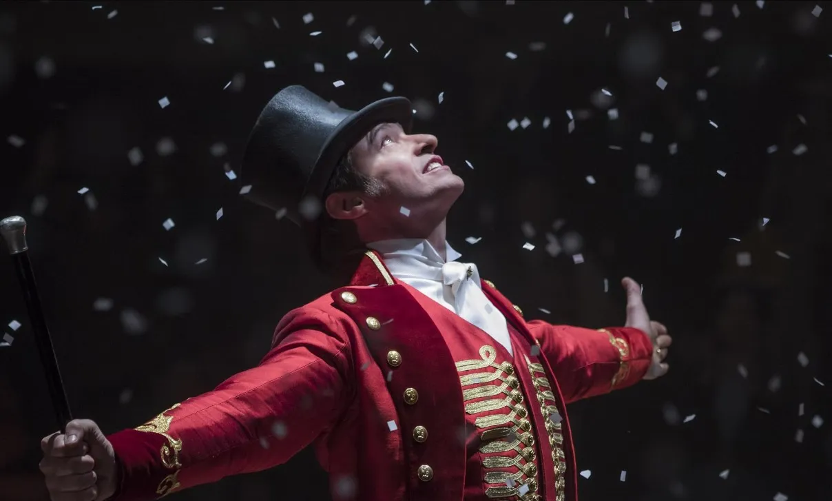 Kırmızı gösterişli ceketi, siyah silindir şapkası ve elindeki bastonuyla P.T. Barnum rolündeki Hugh Jackman, üzerine düşen konfetilerin altında sahnedeki coşkusunu ve karizmasını yansıtan etkileyici bir anla, Hugh Jackman filmleri arasında yer alan The Greatest Showman'daki unutulmaz performanslarından birini sergiliyor.