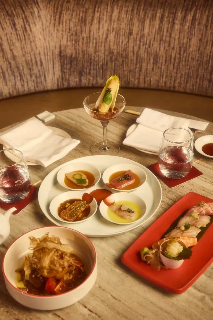 Nobu Istanbul'un özel menüsünden, farklı sunumlara sahip sashimi çeşitleri, üzerinde havyar ve yeşillik bulunan sarma şeklinde bir başlangıç, taze nigiri suşiler ve katsuobushi ile zenginleştirilmiş bir mezenin yer aldığı, Japon mutfağının inceliklerini sergileyen zarif bir gastronomi deneyimi masada duruyor.