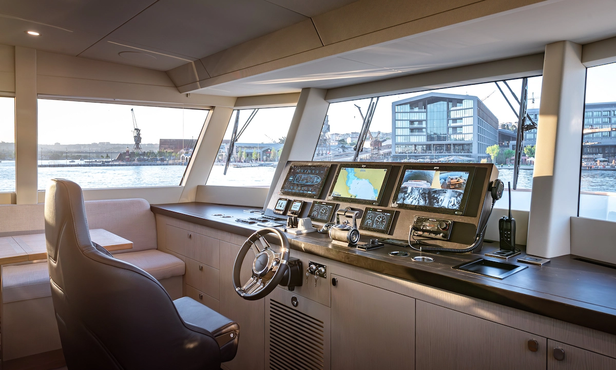 Numarine 27XP yatının geniş cam pencerelerinden şehir ve liman manzarasının görüldüğü modern kaptan köşkünde, ergonomik bir kaptan koltuğu önünde şık bir direksiyon simidi, deniz haritalarını ve gemi verilerini gösteren çok sayıda dijital ekran, telsiz ve kumanda kolları teknolojik bir performans deneyimi sunuyor.