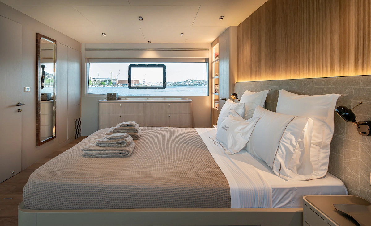 Numarine 27XP yatının bu şık VIP kabini, bej waffle battaniyeli ve beyaz yastıklı geniş yatağı, ahşap detayları ve ambiyans aydınlatmasıyla donatılmış modern iç mekanı, büyük penceresinden görünen sakin deniz manzarasıyla lüks bir misafir deneyimi vaat ediyor.