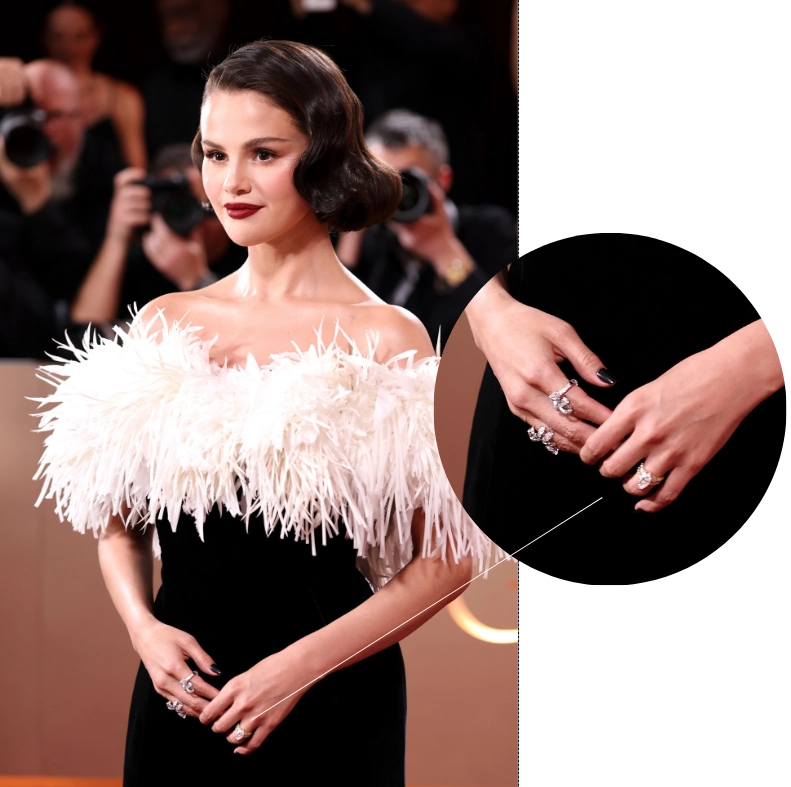 Kırmızı halıda beyaz tüylü, siyah straplez elbisesi ve koyu makyajıyla poz veren Selena Gomez'in, sol el yüzük parmağındaki büyük, markiz kesim nişan yüzüğü yakın çekim detayı, 2026-2027 nişan yüzüğü trendleri arasında öne çıkan celebrity etkisini ve markiz kesimlerin yükselişini vurguluyor.