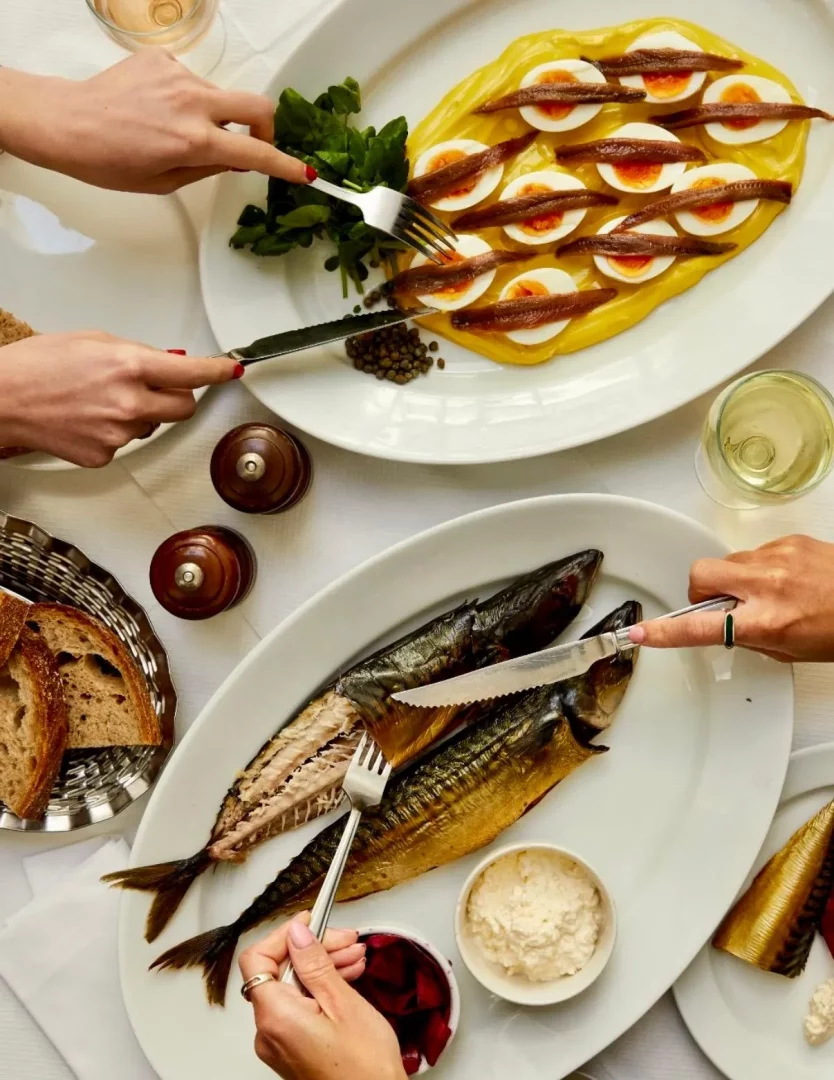 Beyaz bir masa örtüsü üzerinde, St. John restoranının menüsünden iki ana tabağın servis edildiği bir an: bir oval porselen tabakta sarı mayonez üzerinde dizilmiş hamsi filetolu yarım haşlanmış yumurtalar ve su teresi, diğer oval tabakta ise derisi altın rengi füme uskumru balıkları, yanında turşu ve beyaz sos kasesiyle birlikte paylaşılırken eller yemeklere uzanıyor.