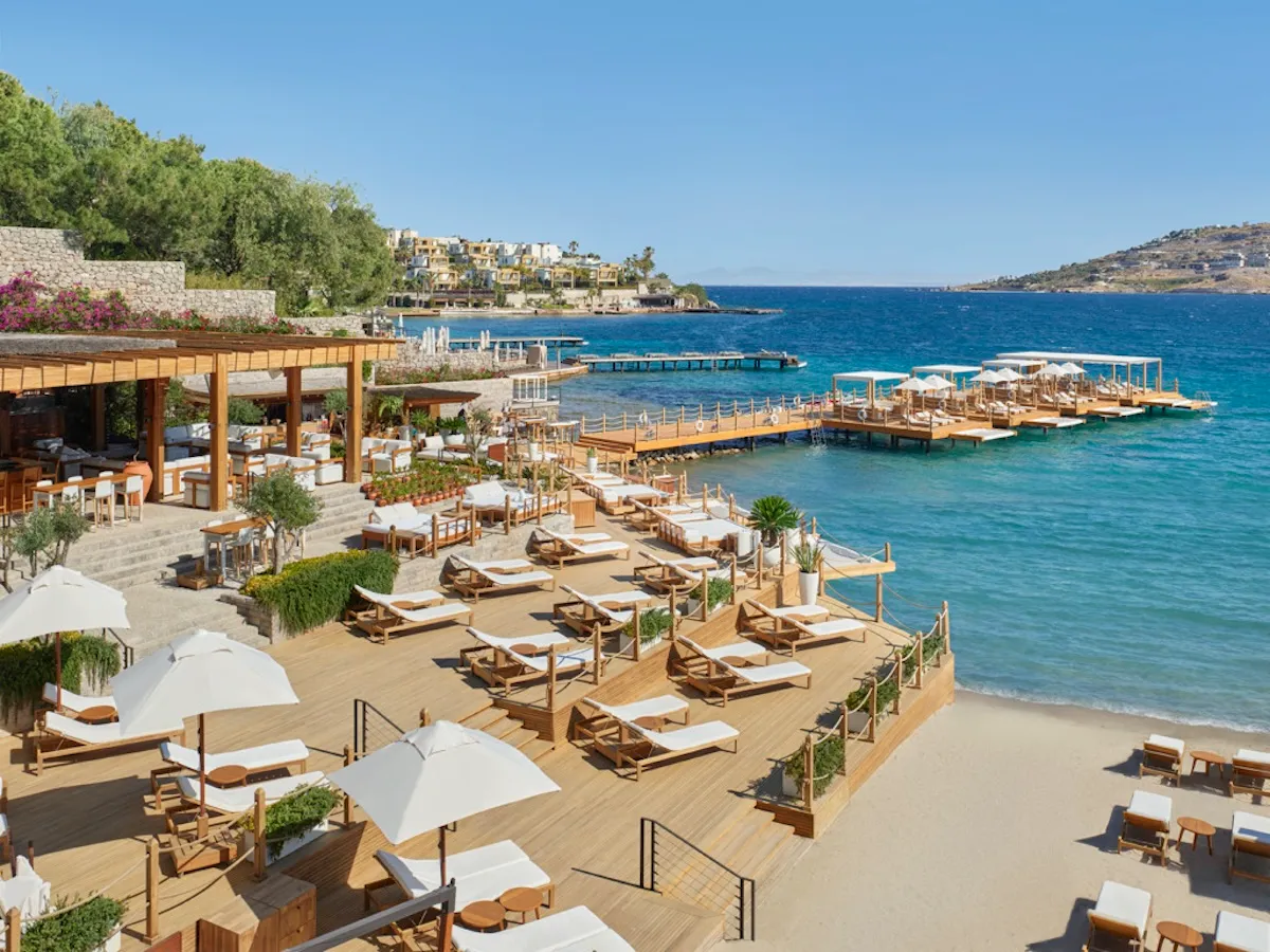 Bodrum'daki The Bodrum Edition otelinin ahşap terasları, denize uzanan şık iskeleleri ve üzerinde beyaz çatılı özel locaslarıyla, berrak turkuaz sulara nazır birçok beyaz şezlongu ve yemyeşil ağaçların süslediği bir lüks dinlenme alanı sunuyor.