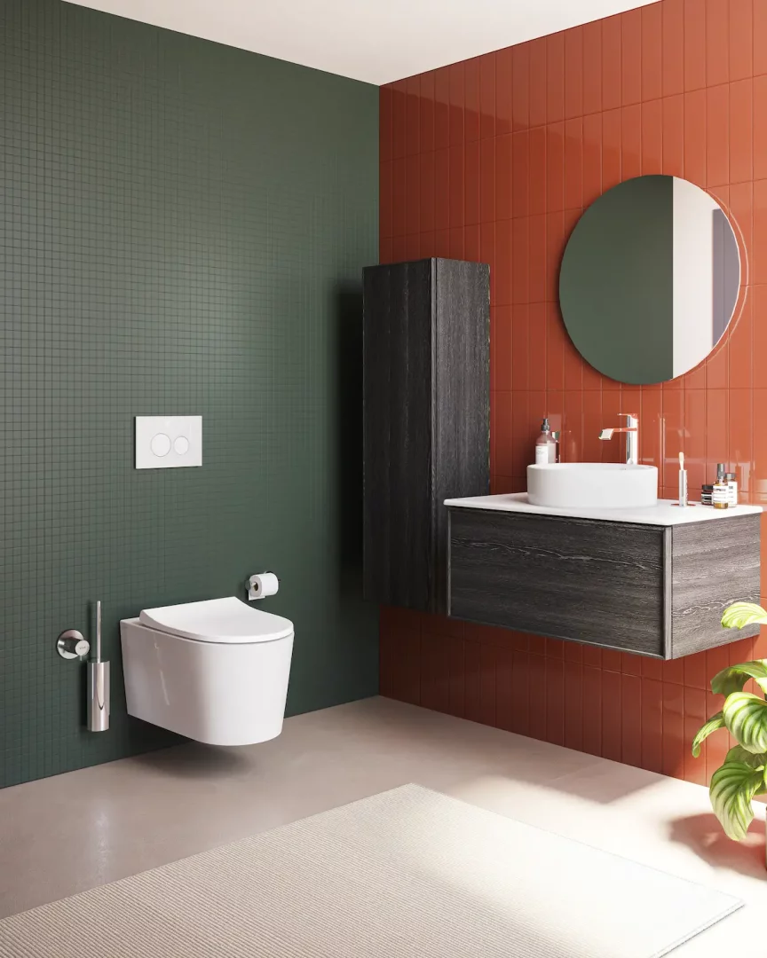 Koyu yeşil mozaik ve terracotta renkli dikey fayanslarla kaplı modern bir banyoda, VitrA QuantumFlush asma klozet ve iki yuvarlak düğmeli minimalist beyaz sifon paneli, koyu ahşap lavabo ünitesi ile uyumlu şık bir tasarım sunuyor.