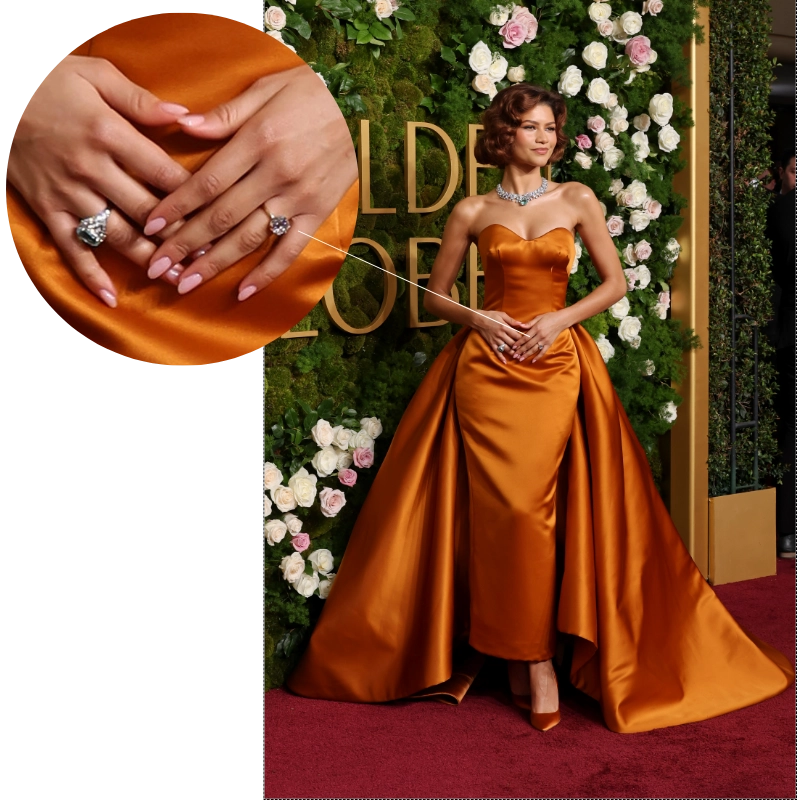 Turuncu straplez elbisesi ve pırlanta kolyeyle kırmızı halıda poz veren Zendaya'nın sol yüzük parmağındaki, 2026-2027 nişan yüzüğü trendlerinden biri olan, east-west yerleşimli, zarif ve modern yüzüğü yakından görülüyor.