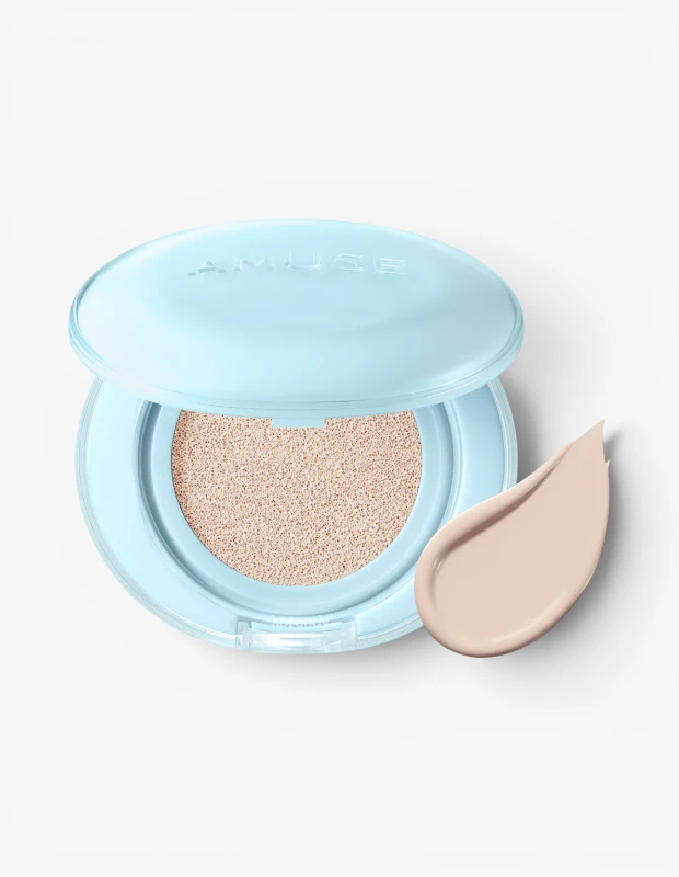 Açık mavi şeffaf kapaklı Amuse Airy Pore Cover Cushion fondöten, içinde görünen açık bej renkli, gözenekleri kapatma vaadiyle hafif dokulu olduğu anlaşılan süngeriyle ve yanında duran damla şeklindeki pürüzsüz fondöten damlasıyla beyaz bir zeminde sergileniyor.