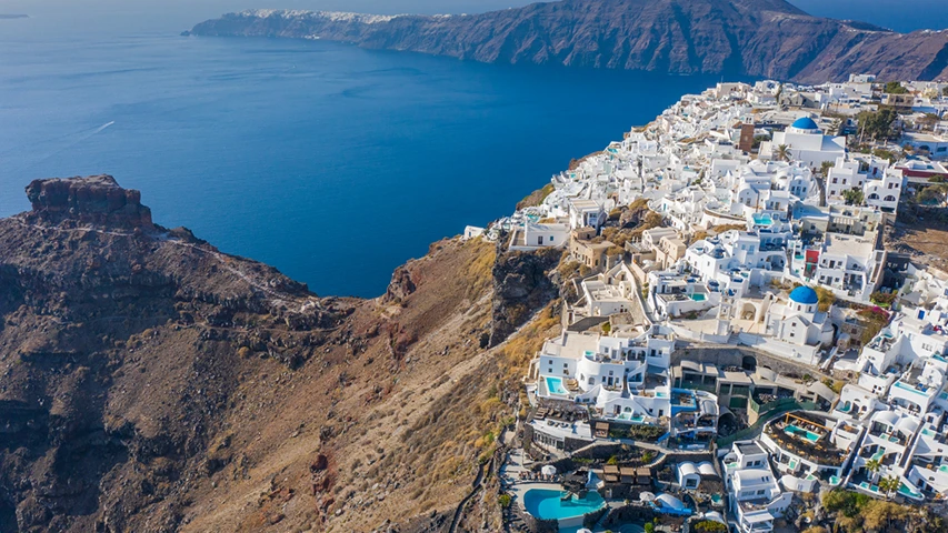 Santorini'deki Skaros Kayalığı'nın yanındaki volkanik yamaçlara oyulmuş, Ege Denizi'ne bakan bembeyaz evleri ve mavi kubbeli kiliseleriyle ünlü bu eşsiz köyün havadan çekilmiş nefes kesici görüntüsü, turkuaz havuzlarıyla birlikte canlı bir yerleşim yerini gözler önüne seriyor.