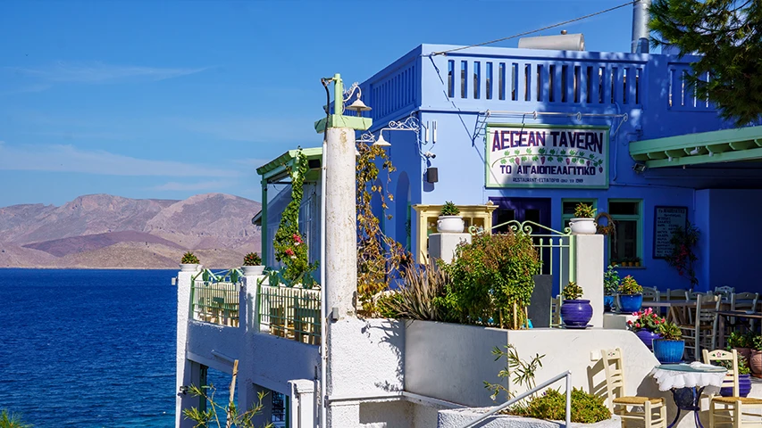 Masmavi Ege Denizi'nin kıyısında, uzaktan yükselen dağ manzarası eşliğinde, tabelasında AEGEAN TAVERN yazan bu şirin mavi beyaz restoran, Kalimnos'ta yöresel yemekleri denemek için teraslarında davetkar bir ortam sunuyor.