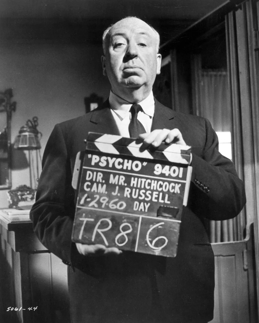 Alfred Hitchcock, ciddi bir ifadeyle objektife bakarak, yönetmenliğini yaptığı ve üzerinde Psycho yazısı ile kendi adının da bulunduğu çekim tahtasını tutuyor, bu siyah beyaz kare onun sinema tarihindeki eşsiz yerini vurguluyor.