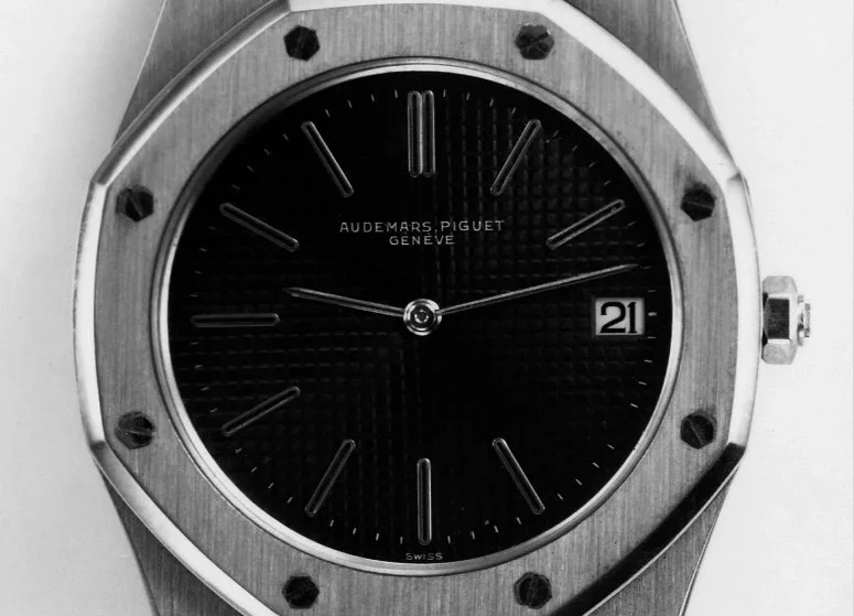 Audemars Piguet Royal Oak'ın yakından çekilmiş, siyah kadranlı ve 21 rakamlı tarih penceresi görünen ilk modelini gösteren bu fotoğraf, Gérald Genta'nın dalış kaskı ilhamlı sekizgen kasası ve belirgin vidalarıyla saatçilik dünyasında tabuları yıkan ikonik Royal Oak tasarımının erken dönemini yansıtıyor.