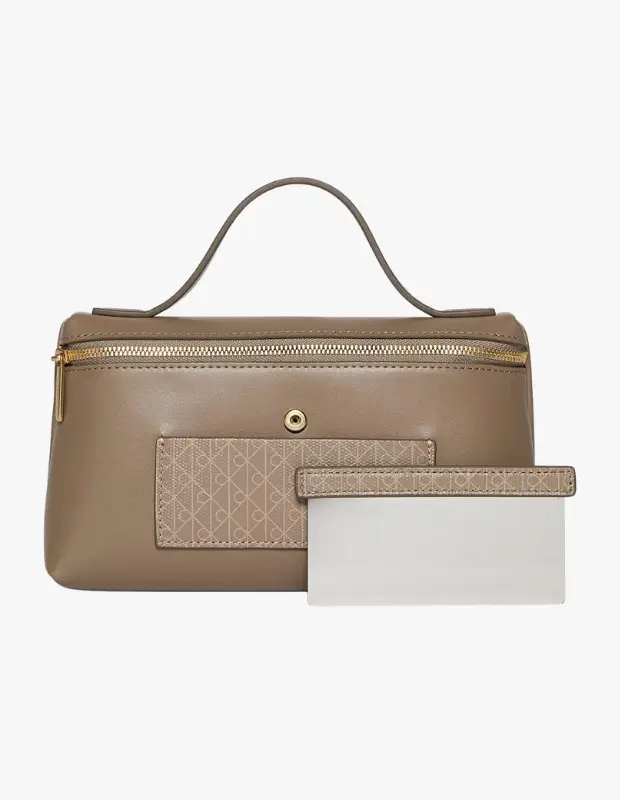 Vizon rengi, altın fermuarlı ve üstten tutma saplı Calvin Klein makyaj çantası, ön yüzündeki zarif CK logolu dokulu cebiyle yaz bavulu ve farklı güzellik rutinleri için şık ve pratik bir seçim sunuyor.