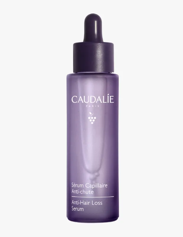 Beyaz Caudalie Paris yazısı, zarif üzüm simgesi ve Fransızca ile İngilizce olarak Sérum Capillaire Anti-chute / Anti-Hair Loss Serum ibaresi bulunan, koyu mor damlalıklı kapağa sahip, yarı saydam açık mor cam bir şişe, saç dökülmesi karşıtı bir ürünü özenle sergiliyor.
