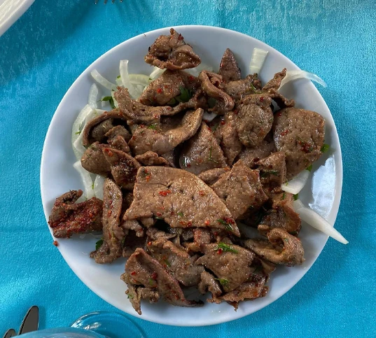 Kınalıada'da yer alan Çınaraltı Kuyu Restaurant'ın mavi örtülü masasında, üzerinde bolca pul biber ve ince dilimlenmiş soğanlarla servis edilmiş, özenle sotelenmiş, lezzetli Arnavut ciğeri yemeği iştah açıcı bir şekilde tabağı dolduruyor.