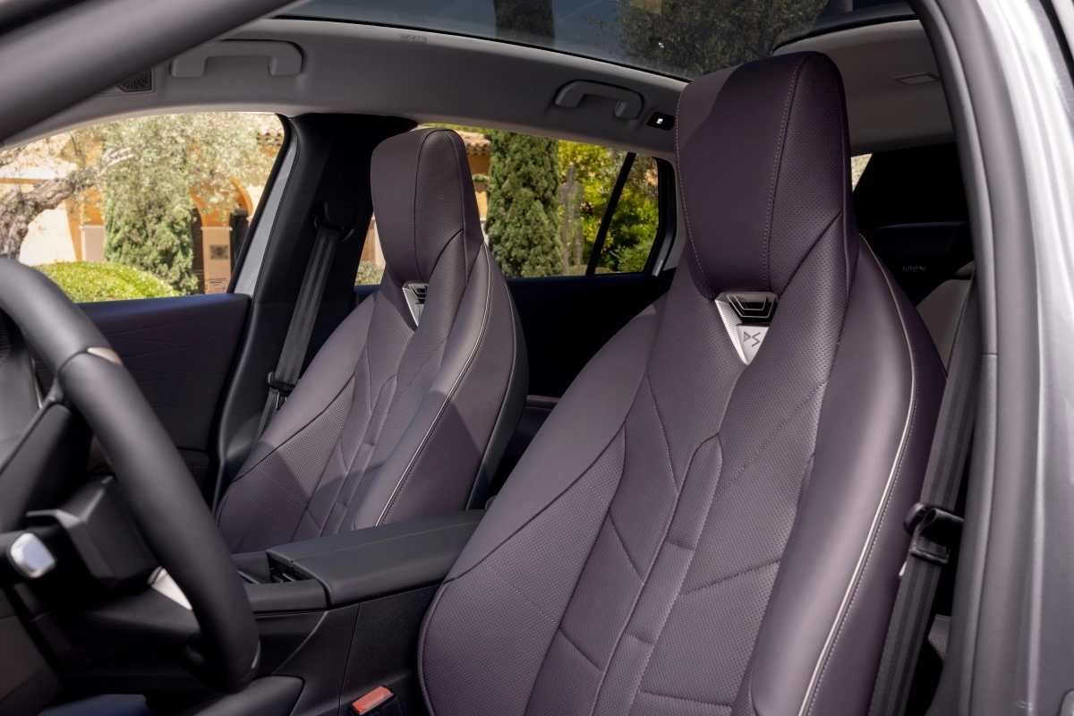Lüks elektrikli premium SUV'nin iç mekanında, koyu renkli delikli deri ön koltuklar, özel dikiş detayları ve koltuk başlıklarındaki DS logosuyla üst düzey konfor sunan ve boyun ısıtma özelliğine sahip şık bir tasarım görülüyor.