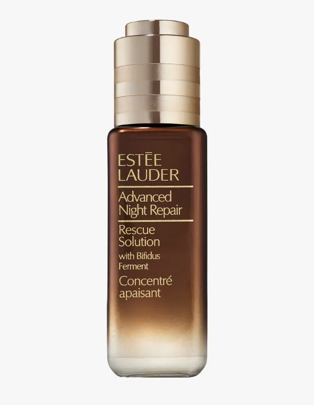Beyaz bir zeminde dik duran, alt kısmı şeffaflaşıp içindeki beyaz sıvıyı gösteren, koyu kahverengi cam şişeli Estée Lauder Advanced Night Repair Rescue Solution cilt bakım ürünü, üzerinde altın renkli yazılarla marka ve with Bifidus Ferment detayları ile metalik altın renkli bir damlatıcı kapağa sahiptir.