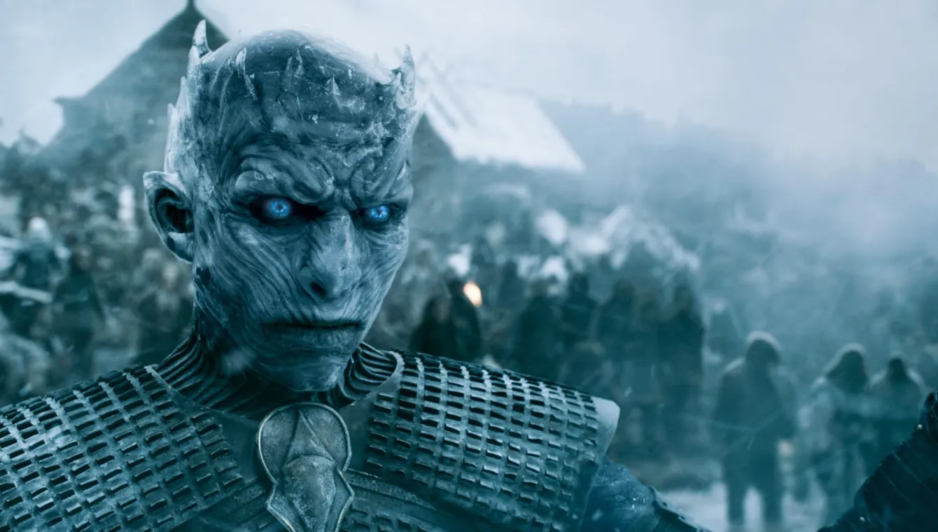 Game of Thrones evreninin gelecekteki büyük tehdidi olan Gece Kralı'nın, buz mavisi teni, ürkütücü derecede parlayan keskin mavi gözleri ve buzdan tacı andıran başındaki çıkıntılarıyla soğuk ve tehditkar duruşu, House of the Dragon'da bahsedilen Ak Gezenler'in Uzun Gece kehanetini çarpıcı bir şekilde görselleştiriyor.