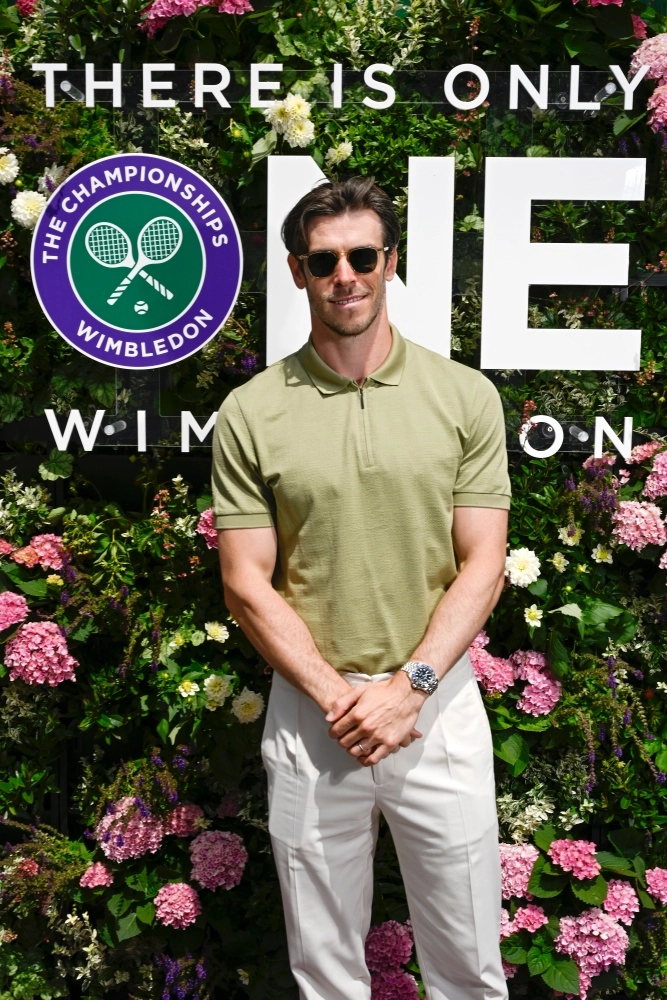 Wimbledon etkinliğinde çiçekli yeşil bir panonun önünde güneş gözlüklü, açık yeşil polo tişörtlü Gareth Bale, sol bileğinde çelik jubile bilezikli ve koyu renk çerçeveli Rolex GMT-Master 2 Batman kol saati ile dikkat çekici bir şekilde poz veriyor.
