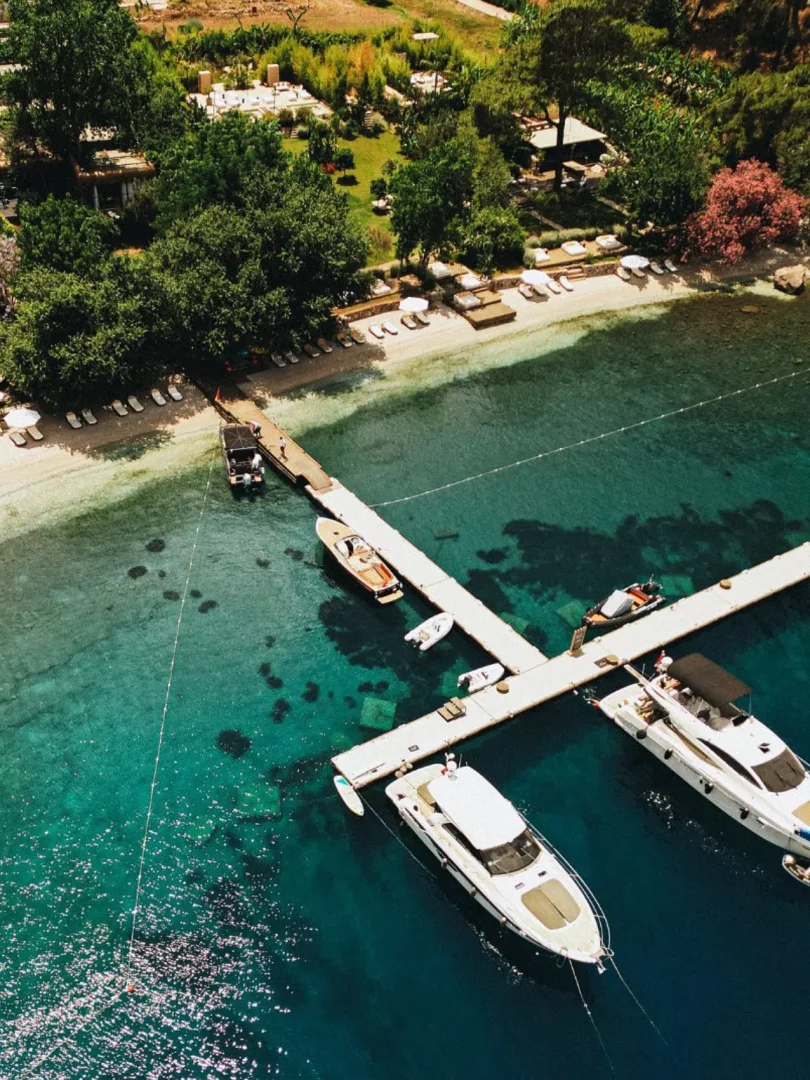 Göcek'te gezilecek yerlerden biri olan bu büyüleyici koyda, yemyeşil ağaçlarla çevrili bir sahil boyunca uzanan beyaz şezlong ve şemsiyeler, kristal berraklığında turkuaz denize uzanan uzun iskele ve iskeleye bağlı lüks yatlar kuşbakışı görüntüsüyle adeta bir cenneti andırıyor.