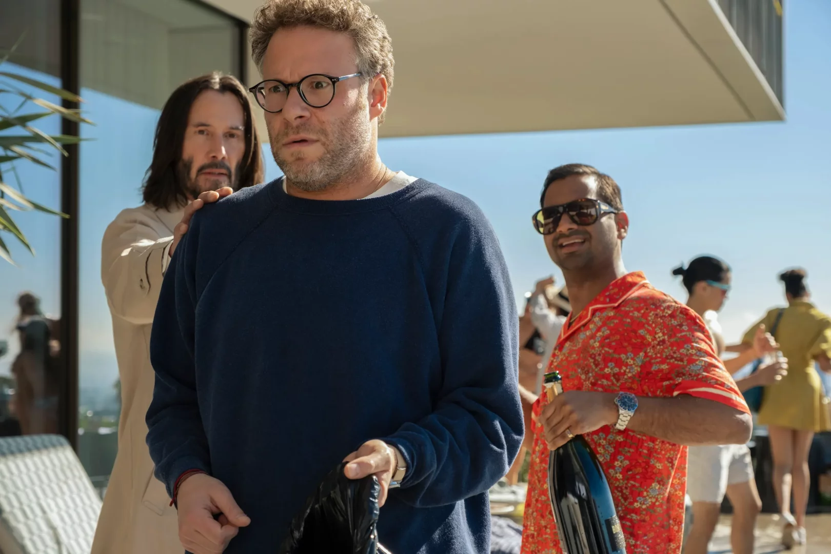 Uzun saçlı ve sakallı Keanu Reeves'in bej ceketiyle omzuna dokunduğu, şaşkın yüz ifadesi ve gözlükleriyle öne çıkan Seth Rogen'ın yanında, güneş gözlüklü ve çiçekli gömlekli Aziz Ansari'nin elinde şampanya şişesiyle gülümsediği bu neşeli sahne, izleme listenize eklemeniz gereken eğlenceli filmler ve dizilerden birini temsil ediyor.