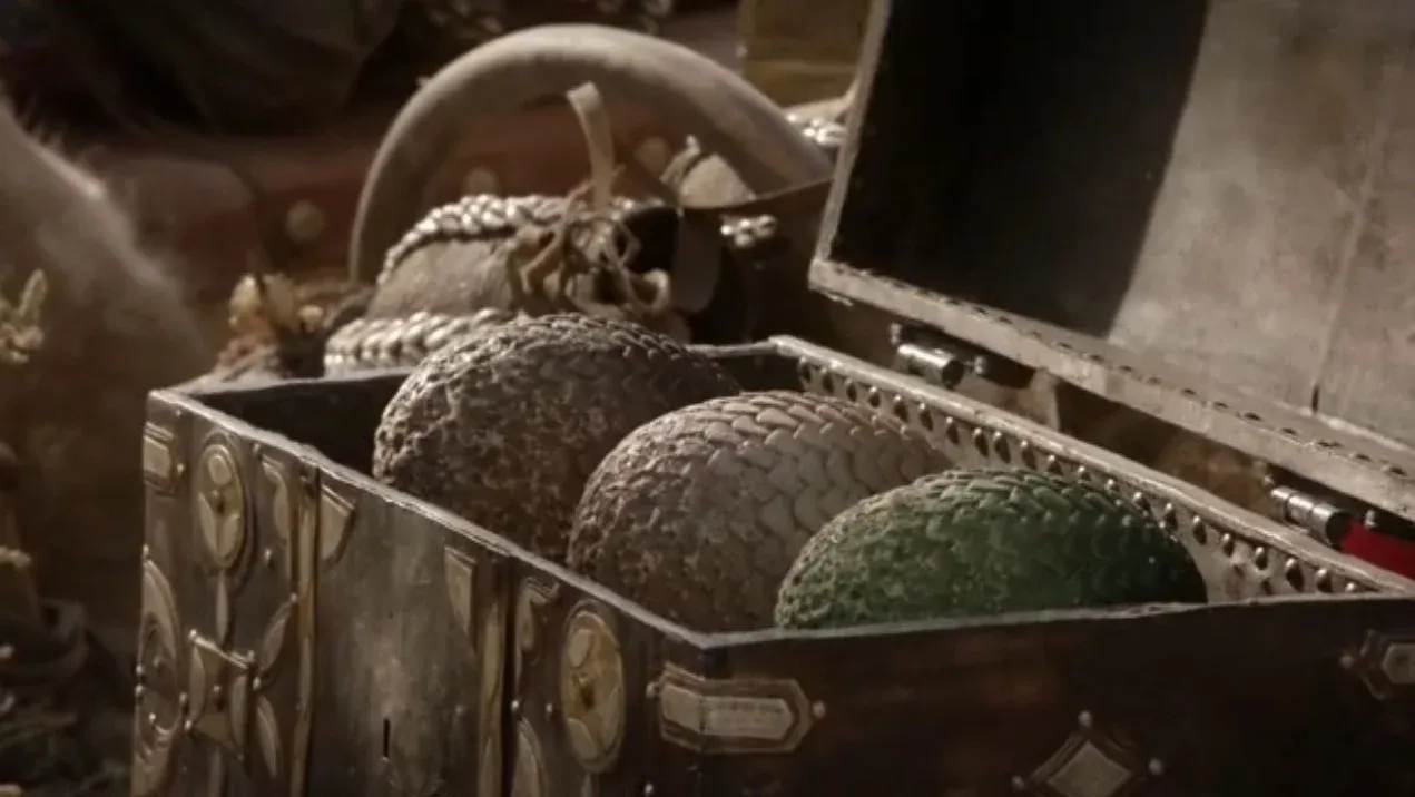 House of the Dragon evreninde, Demir Taht mücadelesi için kritik önem taşıyan ve Targaryen Hanedanı'nın gücünü simgeleyen ejderha yumurtaları, yarı açık, süslü metal detaylı bir sandıkta, koyu kahverengi, açık kahverengi ve parlak yeşil pullu yüzeyleriyle belirgin bir şekilde görülüyor.