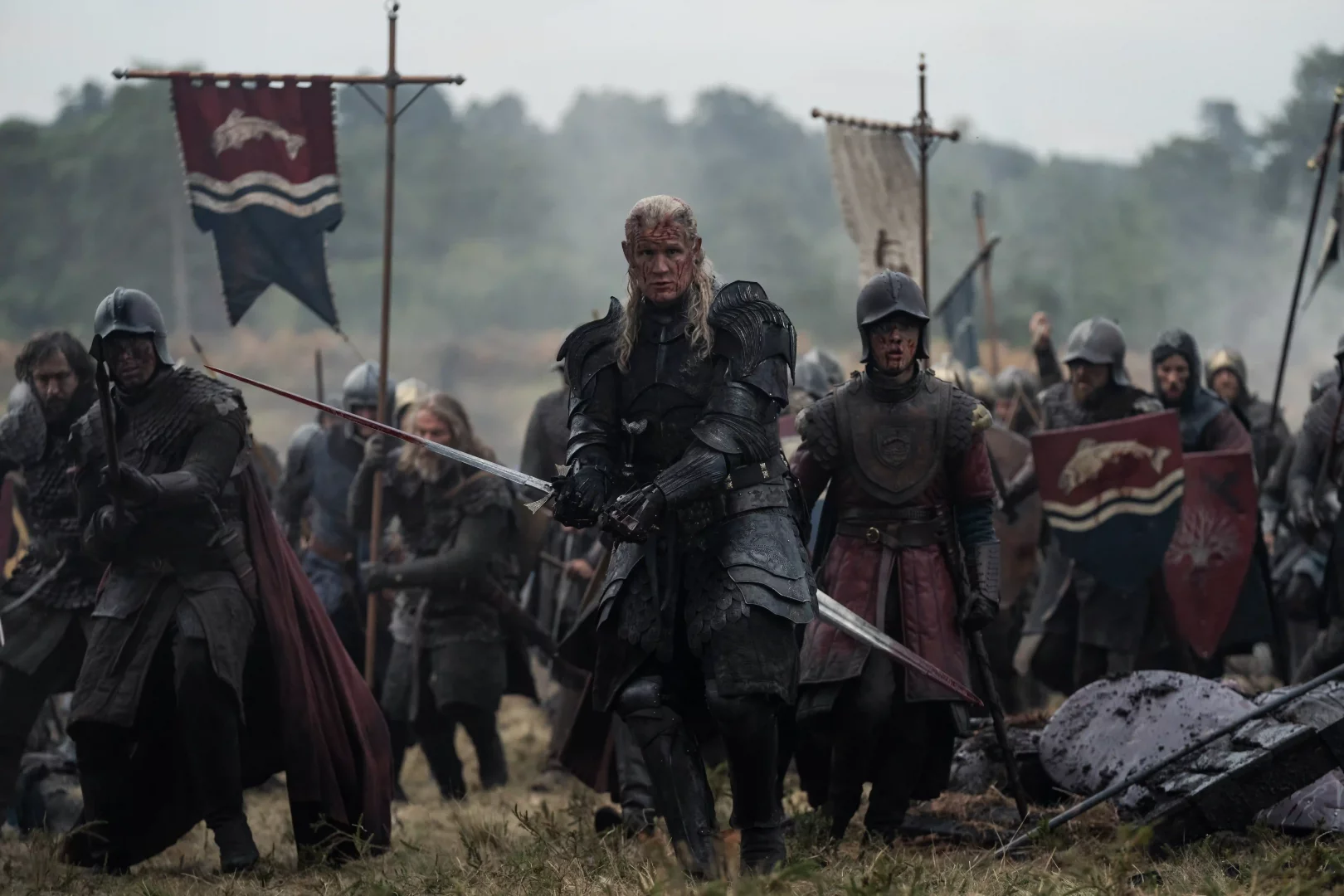 Prens Daemon Targaryen, siyah zırhıyla, yüzündeki kan izleri ve elindeki kanlı kılıcıyla kararlı bir şekilde öne doğru ilerlerken, arkasında savaş yorgunu askerler ve dalgalanan Velaryon sancağıyla House of the Dragon 3. sezonundaki Ejderhaların Dansı'nın acımasız iç savaşını tüm gerçekliğiyle yansıtıyor.