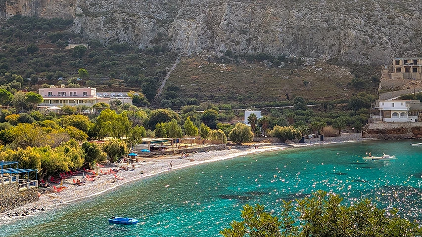 Kalymnos Adası'nın sarp dağ eteklerinde, pırıl pırıl turkuaz sularıyla göz kamaştıran çakıllı bir koy plajı, renkli şezlongları, yemyeşil bitki örtüsüyle çevrili tesisleri ve denizde yüzen teknelerle huzurlu bir atmosfere sahip.