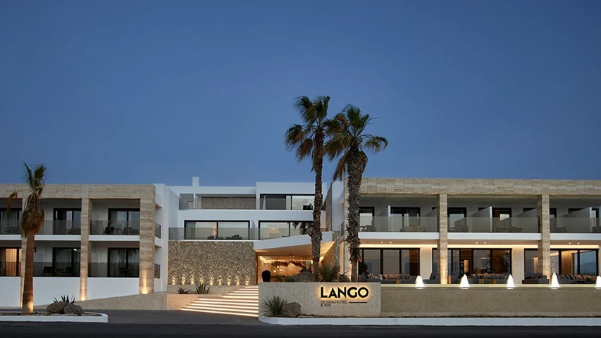 Alacakaranlıkta, çağdaş mimarisi, özenle aydınlatılmış merdivenleri ve cam balkonlarıyla dikkat çeken Lango Design Hotel & Spa'nın modern binası, önündeki palmiye ağaçları ve zarif su öğeleriyle lüks ve huzurlu bir atmosfer sunuyor.