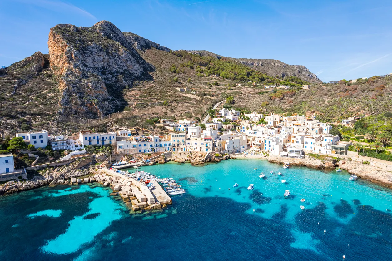 Levanzo Adası'nda, kayalık dağların eteklerine kurulmuş, beyaz badanalı evleri ve mavi panjurlarıyla Akdeniz mimarisini yansıtan büyüleyici bir sahil köyü, turkuaz renkli berrak denizi ve küçük limanıyla huzurlu bir Sicilya manzarasını kuşbakışı sunuyor.