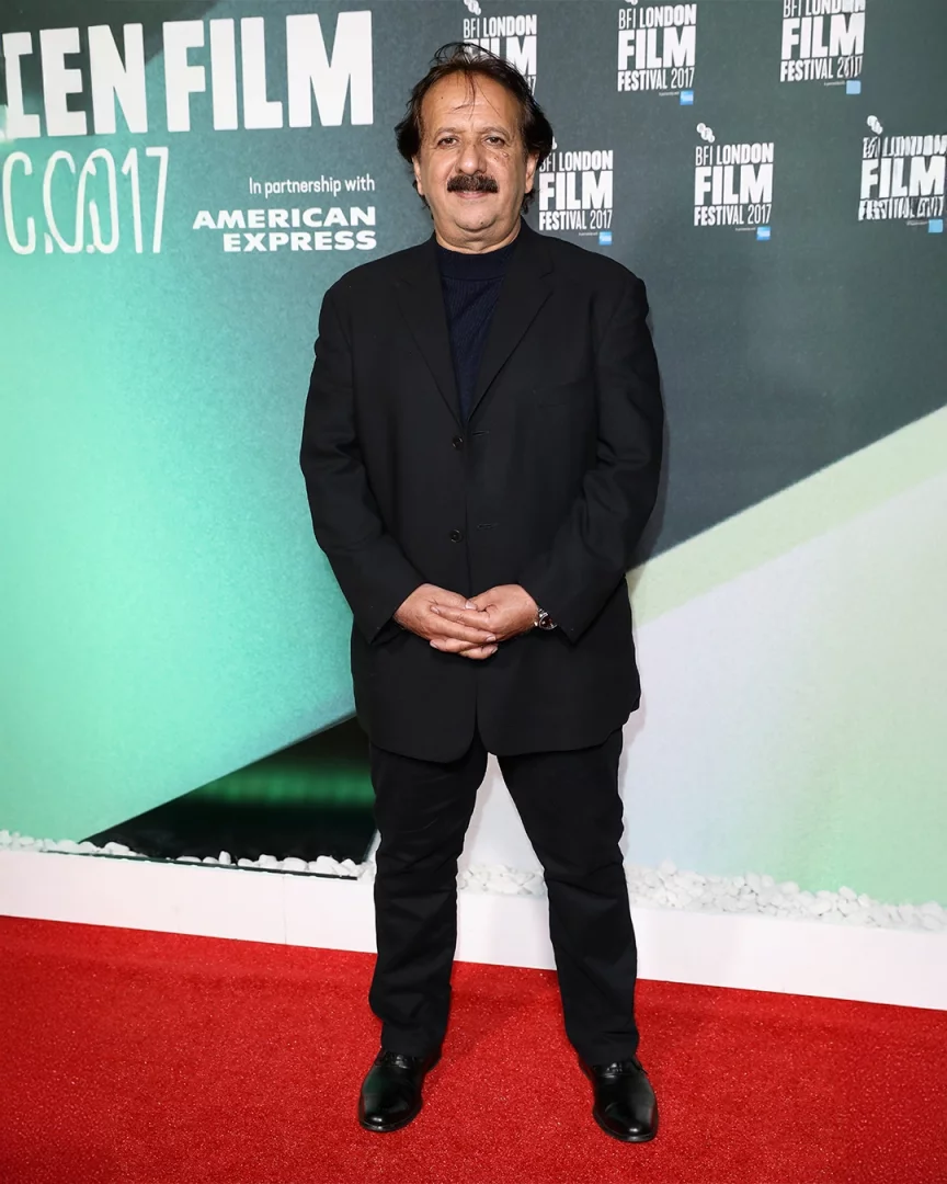 Ünlü İranlı film yönetmeni Majid Majidi, BFI Londra Film Festivali 2017 etkinliğinde, arkasında American Express sponsorluk yazısı ve festival logosunun bulunduğu bir arka plan önünde, siyah takım elbisesiyle kırmızı halıda ellerini kavuşturmuş şekilde duruyor ve hafifçe gülümsüyor.