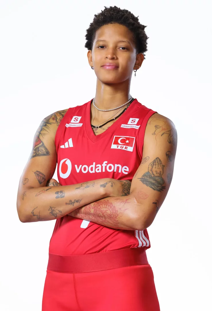 Türk voleybolunun yıldız isimlerinden Melissa Vargas, omuzlarına kadar uzanan dövmeleri ve kolları göğsünde çapraz duruşuyla, üzerinde Türk bayrağı amblemi, Adidas ve Vodafone logoları bulunan kırmızı milli takım formasını giymiş olarak objektife bakıyor.