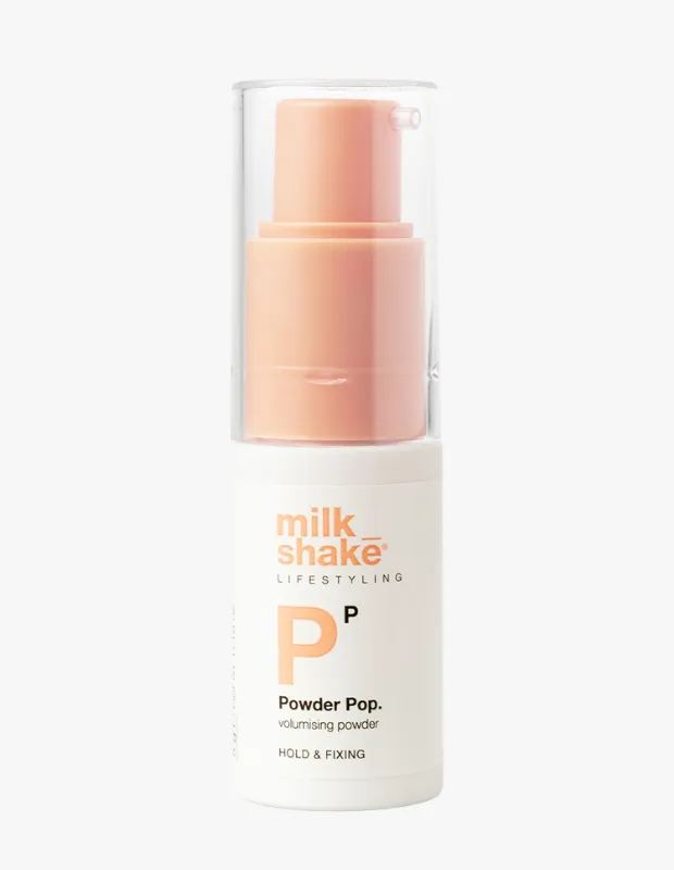Beyaz bir şişe üzerinde milk_shake LIFESTYLING Powder Pop. volumising powder HOLD & FIXING yazılı, şeffaf kapaklı ve şeftali renkli pompalı bir saç şekillendirme ürünü olan hacim verici pudra şişesi, beyaz zeminde dikey olarak konumlanmış.