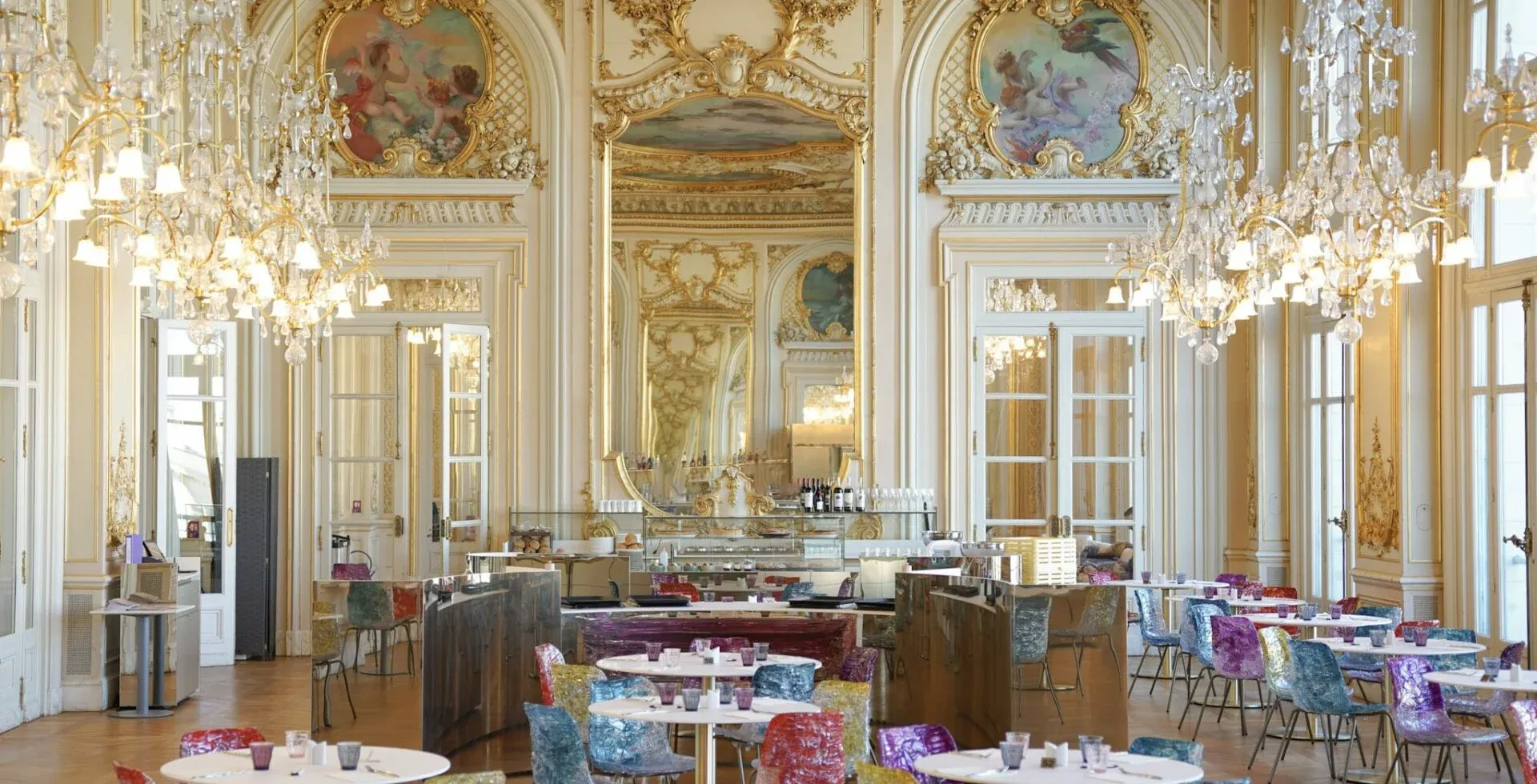 Paris'teki Orsay Müzesi'nin tarihi Belle Époque salonundaki görkemli müze restoranı, altın varaklı duvarları, tavan freskleri ve ışıl ışıl kristal avizelerle süslenmiş olup, çağdaş renkli sandalyelerle modern bir dokunuş kazanarak başlı başına bir seyahat nedeni oluşturuyor.