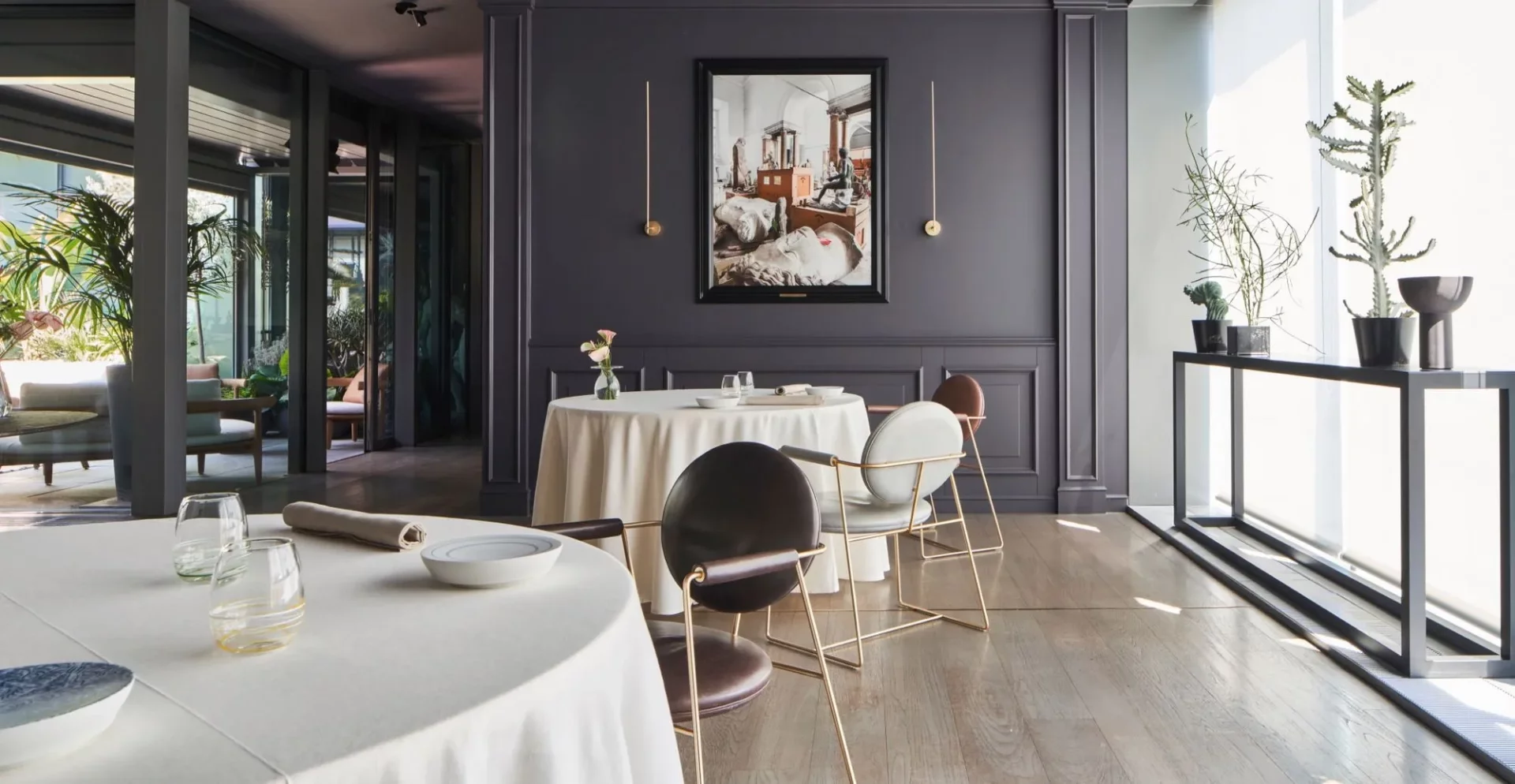 Milano'daki MUDEC'te bulunan bu müze restoranı, koyu gri panelli duvarında klasik heykelleri barındıran bir tablo, modern altın çerçeveli sandalyeler ve bembeyaz örtülü masalarıyla çağdaş tasarımı ve gastronomiyi harmanlayan zarif bir iç mekân sunarak, dışarıdaki yemyeşil bahçeye açılan geniş camlarıyla bütünleşiyor.