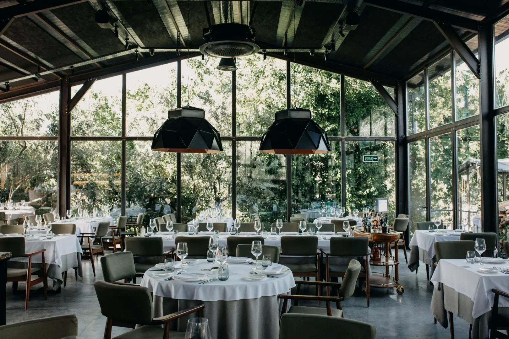 Urla'da yer alan, cam duvarları sayesinde yemyeşil doğa manzarasına sahip bu geniş ve şık restoranda, beyaz örtülü yuvarlak ve kare masalar, koyu yeşil sandalyelerle düzenlenmiş olup, modern tasarım öğeleri ve ışıklandırmalarla zarif bir yemek atmosferi sunuyor.