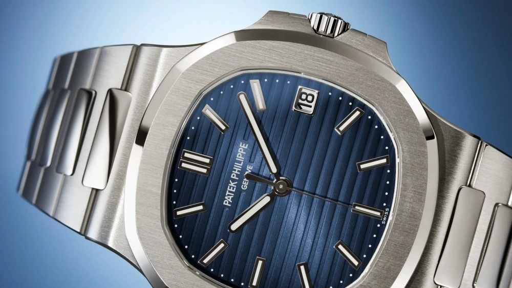 Fırçalanmış beyaz altın kasa ve bileziğiyle göz alıcı Patek Philippe Nautilus 5811 lüks kol saati, belirgin yatay çizgili lacivert kadranı, parlak ibreleri, indeksleri ve saat üçte görünen 18 tarih penceresiyle yakından gösteriliyor.