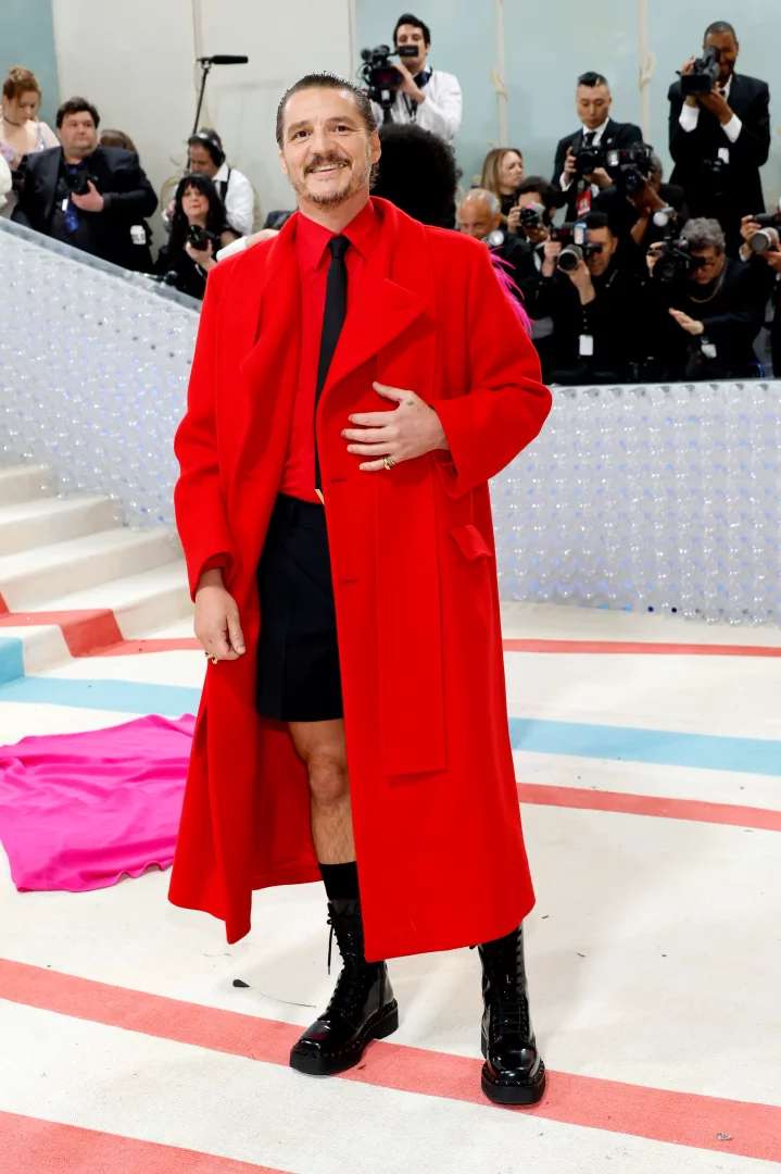 2023 Met Gala etkinliğinde Pedro Pascal, uzun ve dikkat çekici kırmızı paltosu, kırmızı gömleği, siyah kravatı, siyah şortu, tüylü bacakları, siyah çorapları ve bağcıklı parlak botlarıyla, geriye taranmış saçları ve bıyığıyla hafifçe gülümseyerek elini karnına koyarak kameralara poz veriyor.