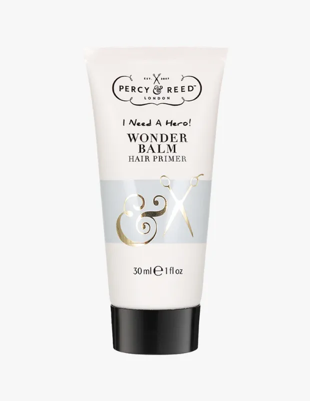 Beyaz zemin üzerinde, siyah kapaklı, Percy & Reed London markalı ve I Need A Hero! Wonder Balm Hair Primer yazılı, gümüş bant üzerinde altın renkli & işareti ve makas detayları bulunan 30 ml'lik bir saç primeri tüpü.