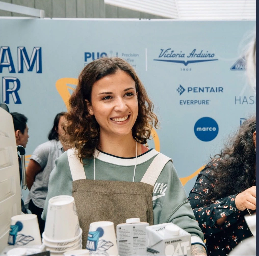 Pınar Mısırdal'ın profesyonel bir fotoğrafı, kameraya doğrudan bakarken sıcak ve kendinden emin bir gülümseme sergiliyor, koyu renk saçları özenle taranmış, şık bir blazer giyiyor ve arkasında hafifçe bulanık bir fon var.