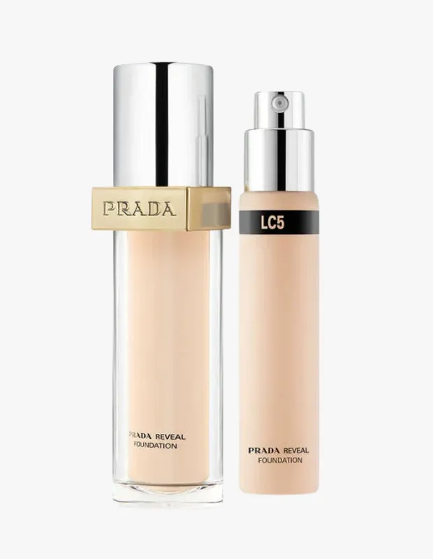 Şeffaf cam pompalı büyük boy bir şişe ve üzerinde LC5 renk kodu bulunan, dar, spreyli küçük bir şişe olmak üzere açık ten rengi Prada Reveal Skin-Optimizing Fondöten ürünleri beyaz bir arka plan üzerinde dikkat çekiyor.