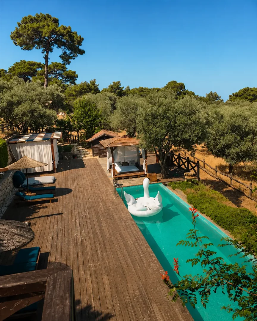 Kaş'taki Prima Donna Hotel'in yemyeşil doğayla iç içe dinlenme alanında, turkuaz renkteki uzun havuzda beyaz bir kuğu şamandırası yüzerken, ahşap terasta şezlonglar ve gölgelikli dinlenme kabinleri misafirleri beklemektedir.