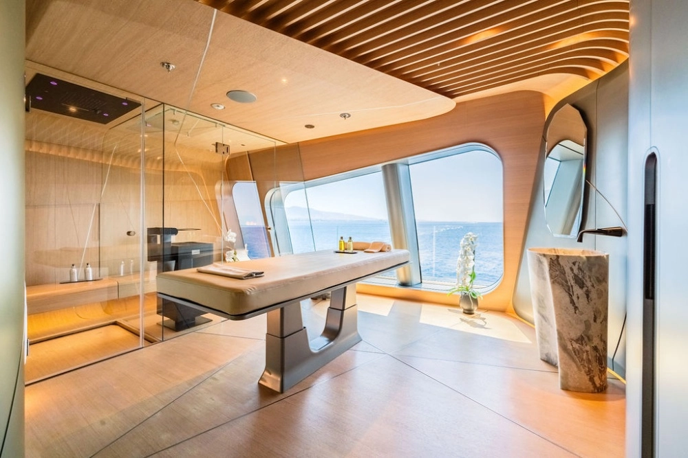 Okyanusun engin manzarasına nazır modern bir süper yat içinde yer alan bu lüks spa wellness alanı, cam duvarlı duşu, masaj yağları ve havlularla düzenlenmiş masaj yatağı, zarif mermer lavabosu ve ahşap detaylarıyla huzurlu bir ortam sunuyor.